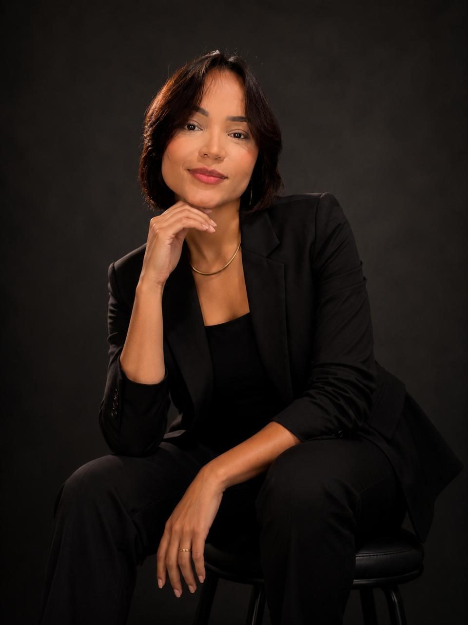Luana Araújo, fisioterapeuta, sentada de blazer preto